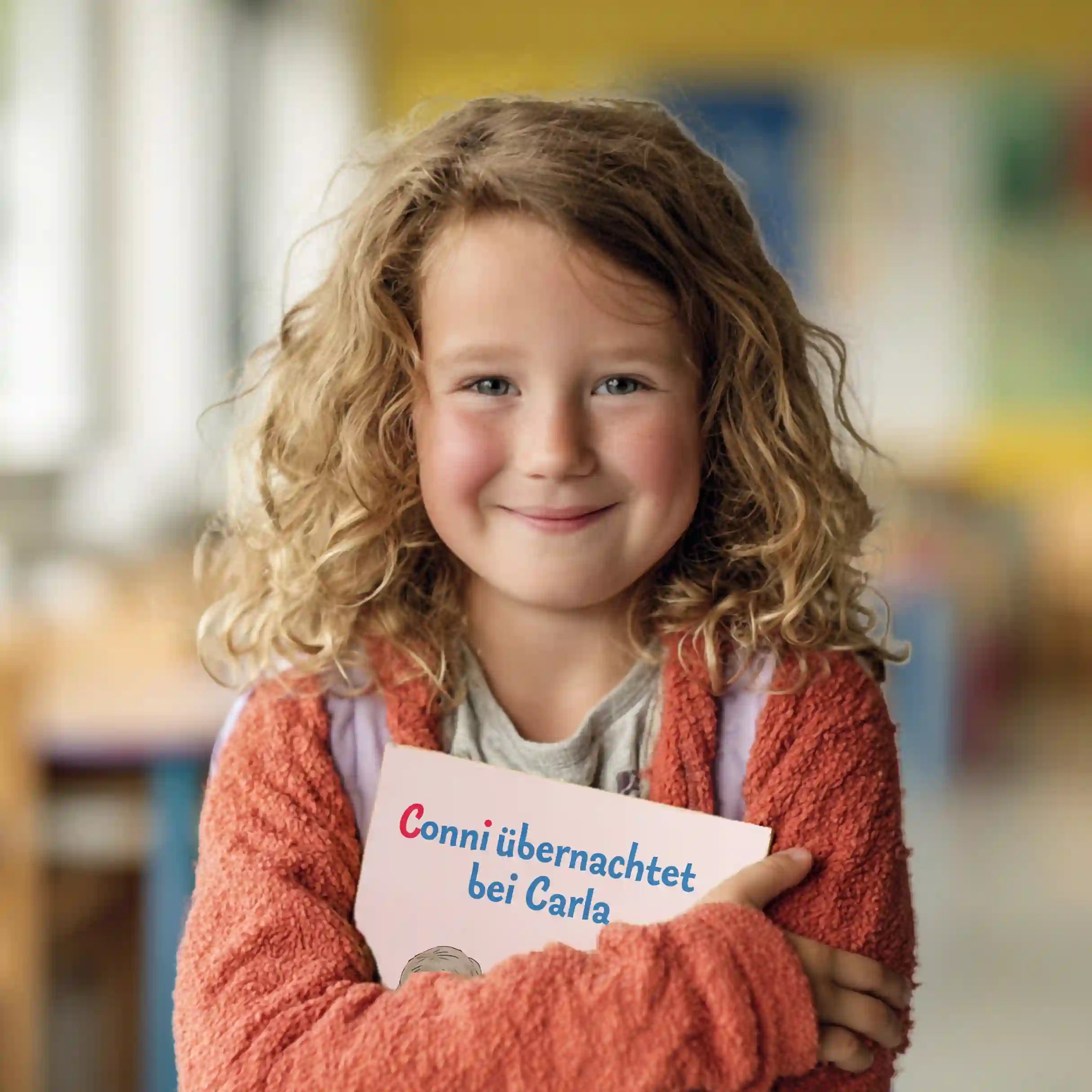 Mädchen hält freudig strahlend das personalisierte Buch "Conni übernachtet bei Carla" im Arm