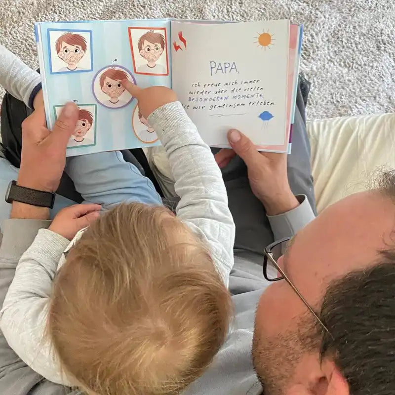 Ein Mann und ein Kind sitzen auf einer Couch und lesen "Für den weltbesten Papa" von Framily. Das Kind zeigt auf eine Illustration, während der Mann das Buch aufgeschlagen hält. Dieses personalisierte Buch ist ein einzigartiges Geschenk für Papa.