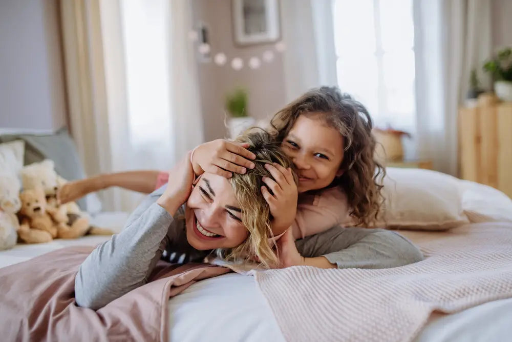 Mutter und Tochter toben auf dem Bett