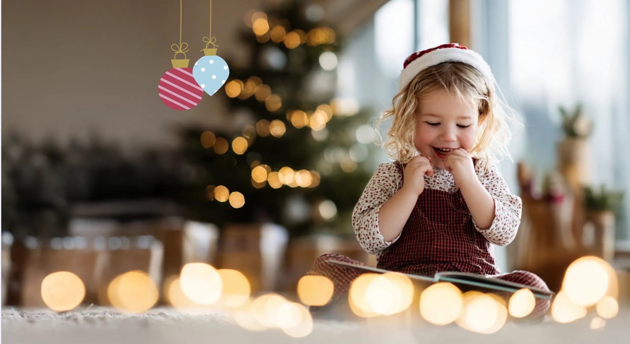 Lächelndes Mädchen liest ein Buch vor einem festlich geschmückten Weihnachtsbaum.